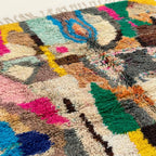 Close-up of the Tifran Boujaad rug showing plush cream wool with multicolor abstract patchwork forms