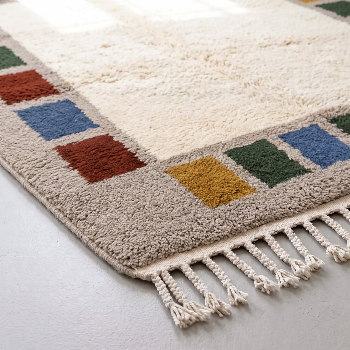 Corner detail showing colour block arrangement and fringe, rust and mustard squares on grey border