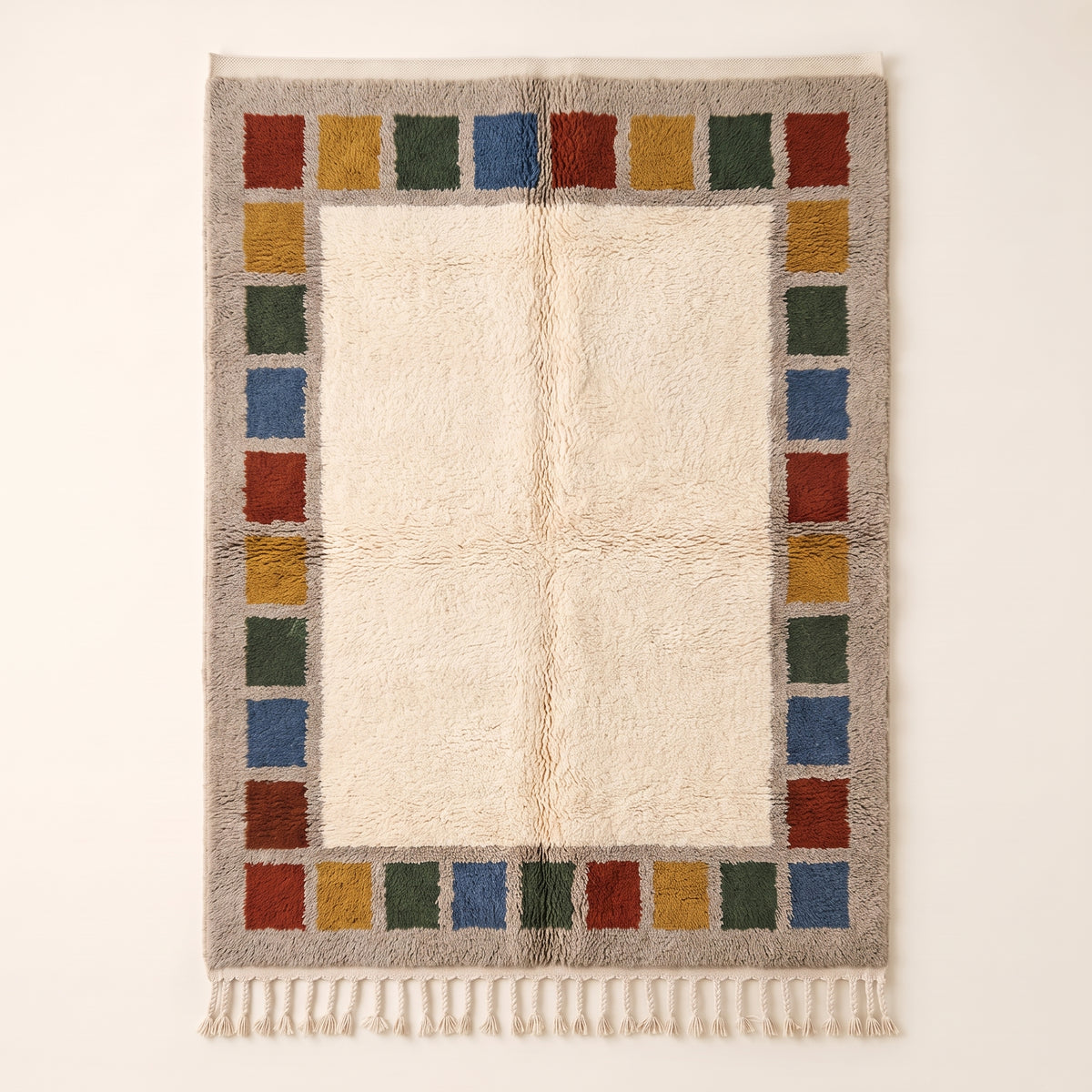 Cream Mrirt rug with colour block border frame in rust, mustard, forest green and slate blue stacked squares, flat lay on plain background