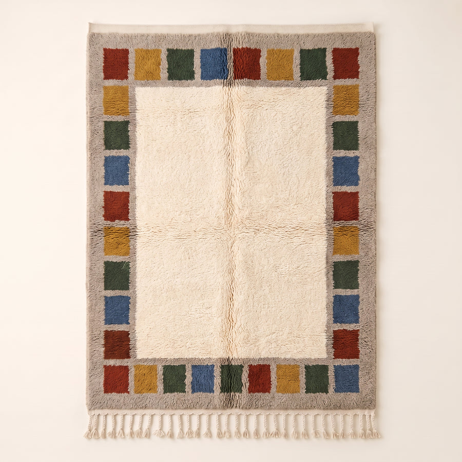Cream Mrirt rug with colour block border frame in rust, mustard, forest green and slate blue stacked squares, flat lay on plain background