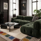 Cream Mrirt rug with colour block border in dark interior with green sofa and black coffee table