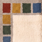 Angled pile detail showing depth and texture of cream field with colour blocks in rust, mustard, green and blue