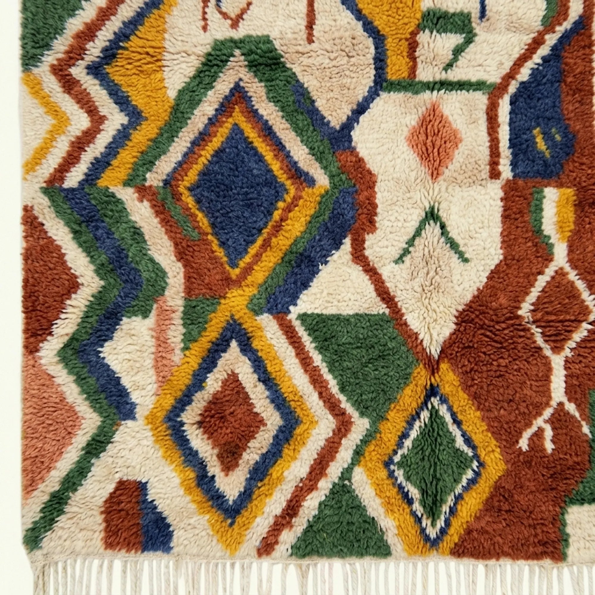 Fringe and edge detail of Asifran beside layered cream, forest green and terracotta geometric bands