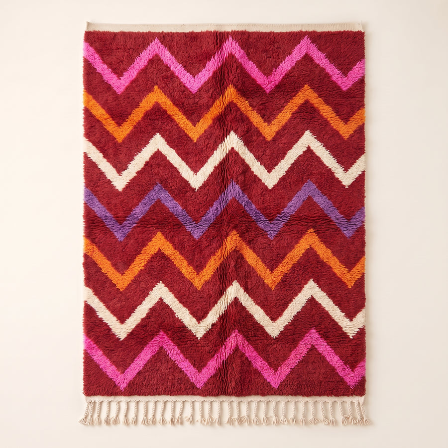 Flat view of crimson Boujaad rug with horizontal chevron stripes in magenta, orange, ivory and periwinkle