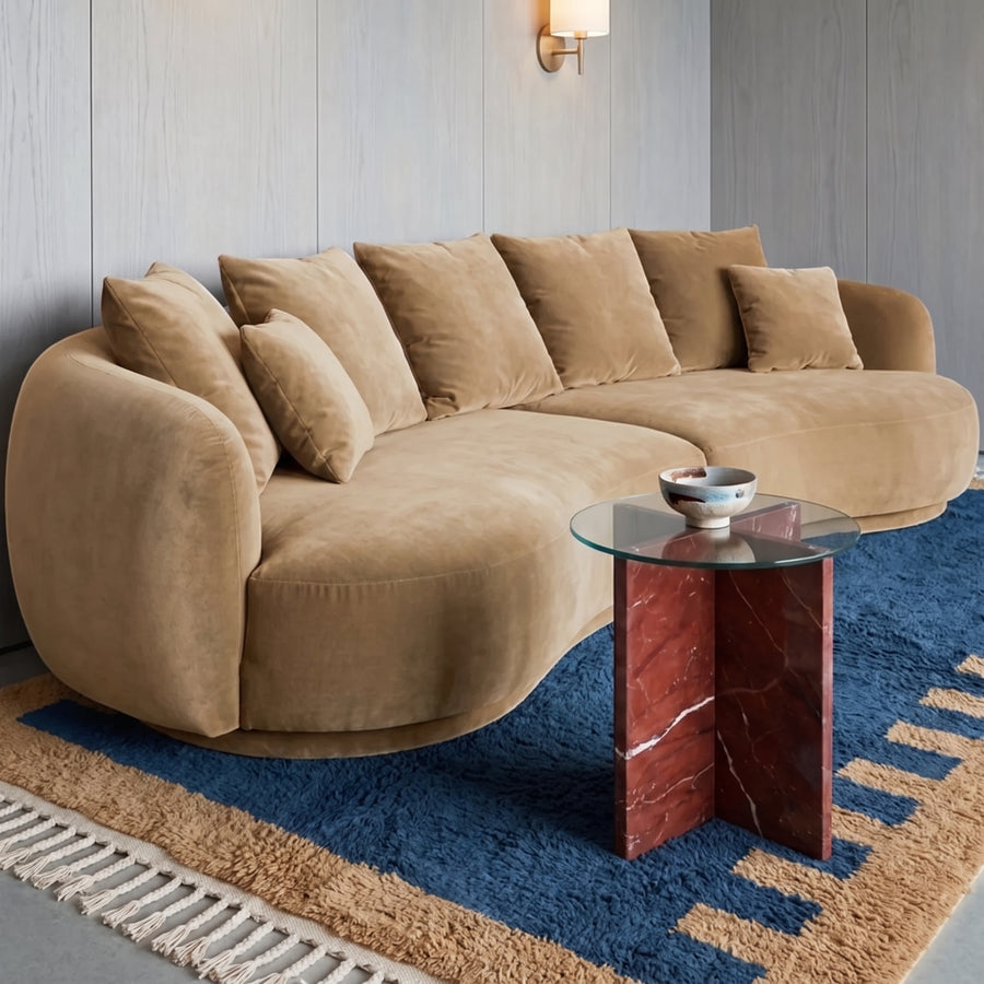 Denim and camel Mrirt rug in living room under curved beige sofa with glass and marble side table