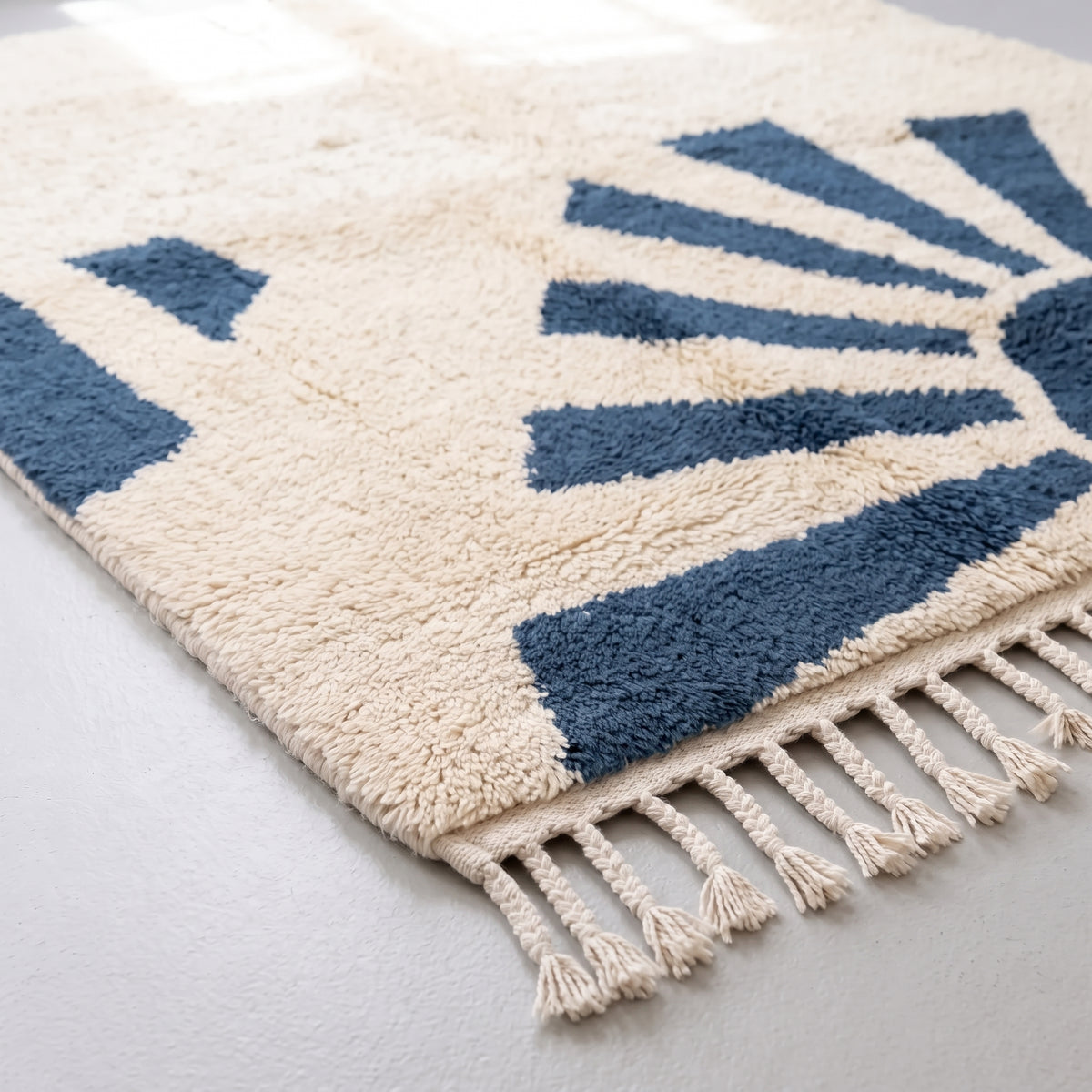 Corner detail of denim & ivory rug showing fringe edge and pile construction