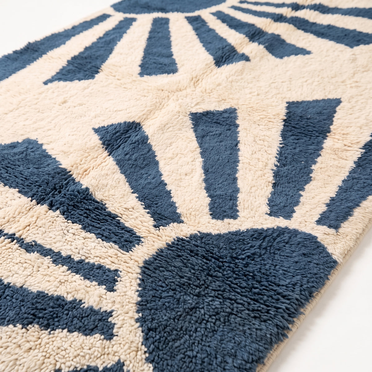 Close-up of knotted wool pile showing denim and ivory radiant bands texture and depth