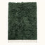 Forest green Beni Ourain rug Tafrara with textured pile and ivory fringe, flat lay on plain background
