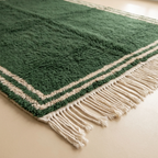 Corner and hand-tied fringe detail of the Tafukt green and ivory wool rug.
