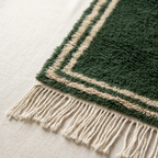 Ivory double border and fringe craftsmanship on the Tafukt forest green rug.