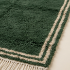 Close view of the ivory double border framing the Tafukt forest green rug.