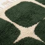 Border detail of the Anir forest green and ivory rounded grid rug.