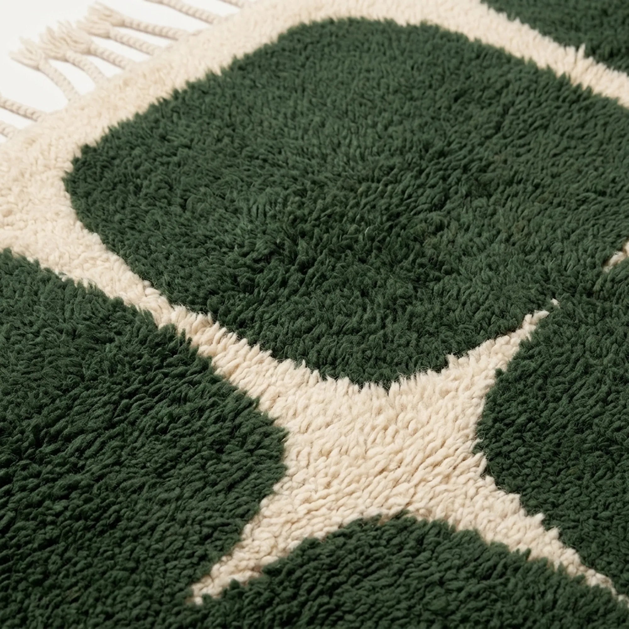 Border detail of the Anir forest green and ivory rounded grid rug.