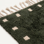 Close-up of the forest green and ivory wool rug border.
