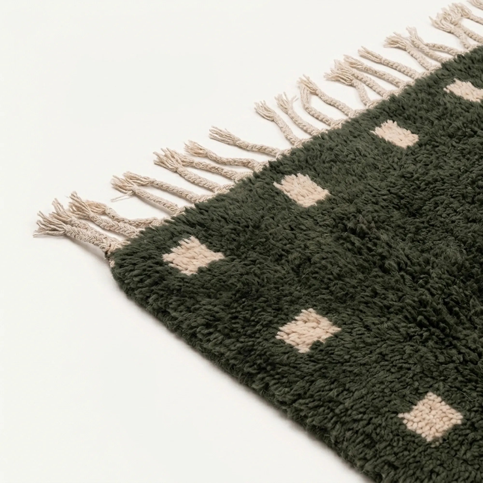 Angled detail of the forest green and ivory hand-knotted wool rug.