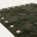 Fringe and border detail of the forest green and ivory Moroccan wool rug.