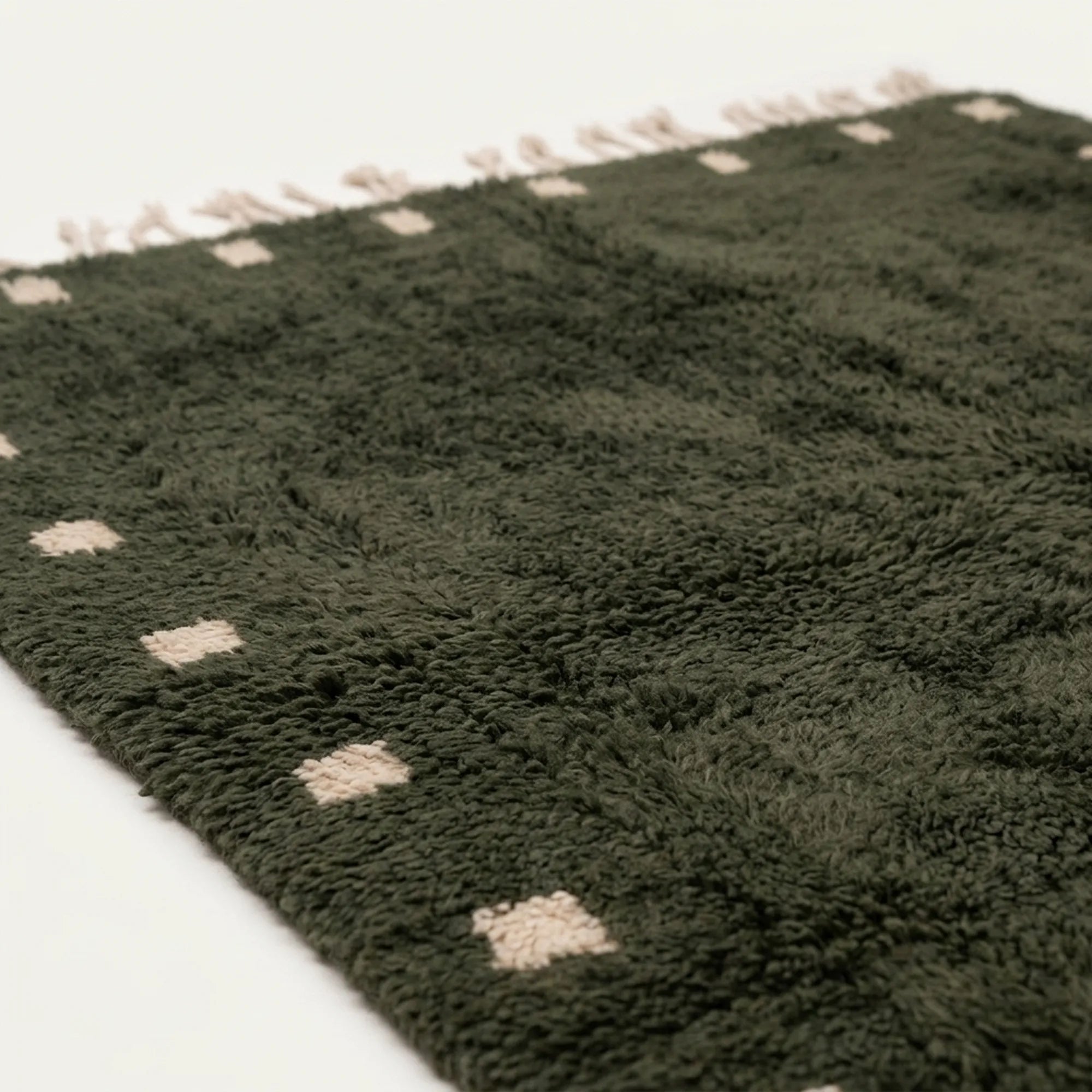 Fringe and border detail of the forest green and ivory Moroccan wool rug.