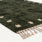 Handmade texture and edge detail of the forest green and ivory wool rug.