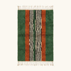 Full view of the Tanit forest green, terracotta, ivory and black Beni Ourain rug with a central stripe design.