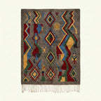 Full view of the Abridan Boujaad rug in gray, blue, red, green and ochre with scattered diamonds and zigzag symbols
