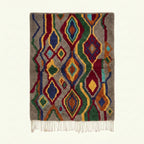 Full view of the Tazallit Boujaad rug in gray, red, green, blue and ochre with layered diamond and wavy line motifs