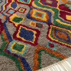 Close-up of the Tazallit Boujaad rug showing plush gray wool with red, green, blue and ochre diamond motifs