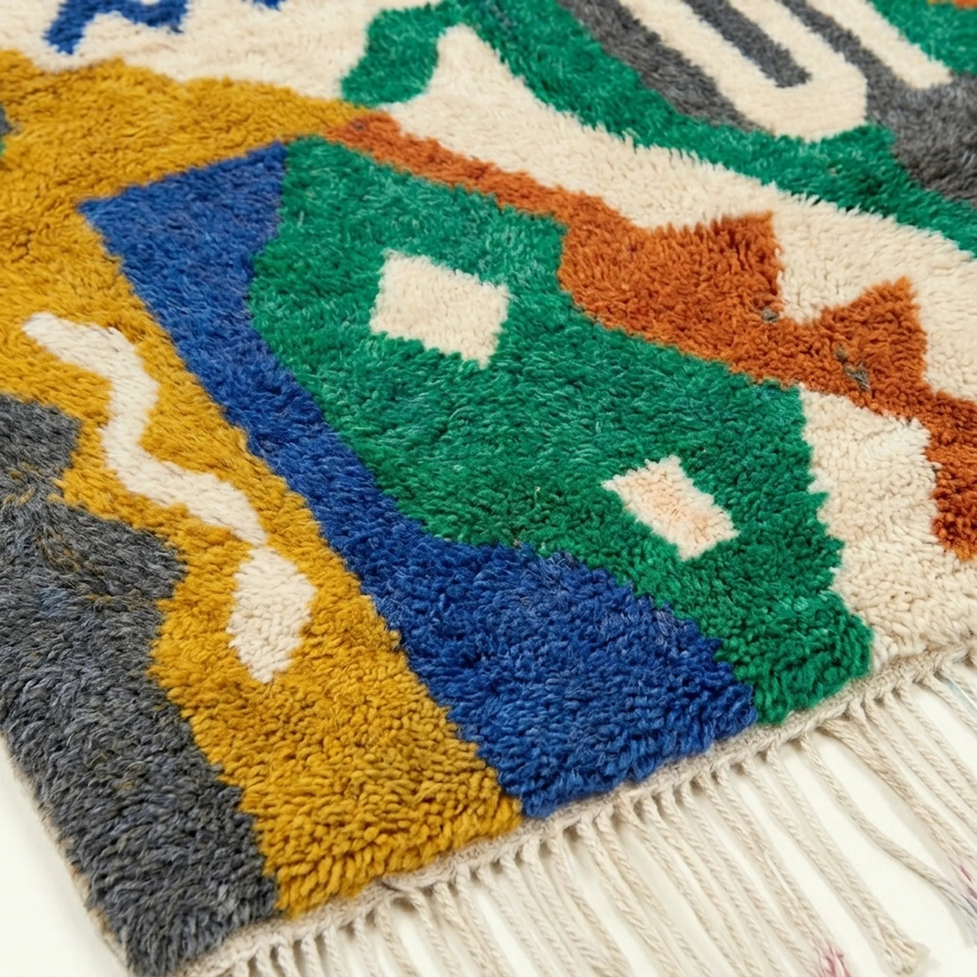 Detailed view of Awragh showing a green shield-like motif, cobalt field and terracotta linear accents