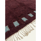 Close-up of the burgundy and ivory border block motif on the Idir rug.