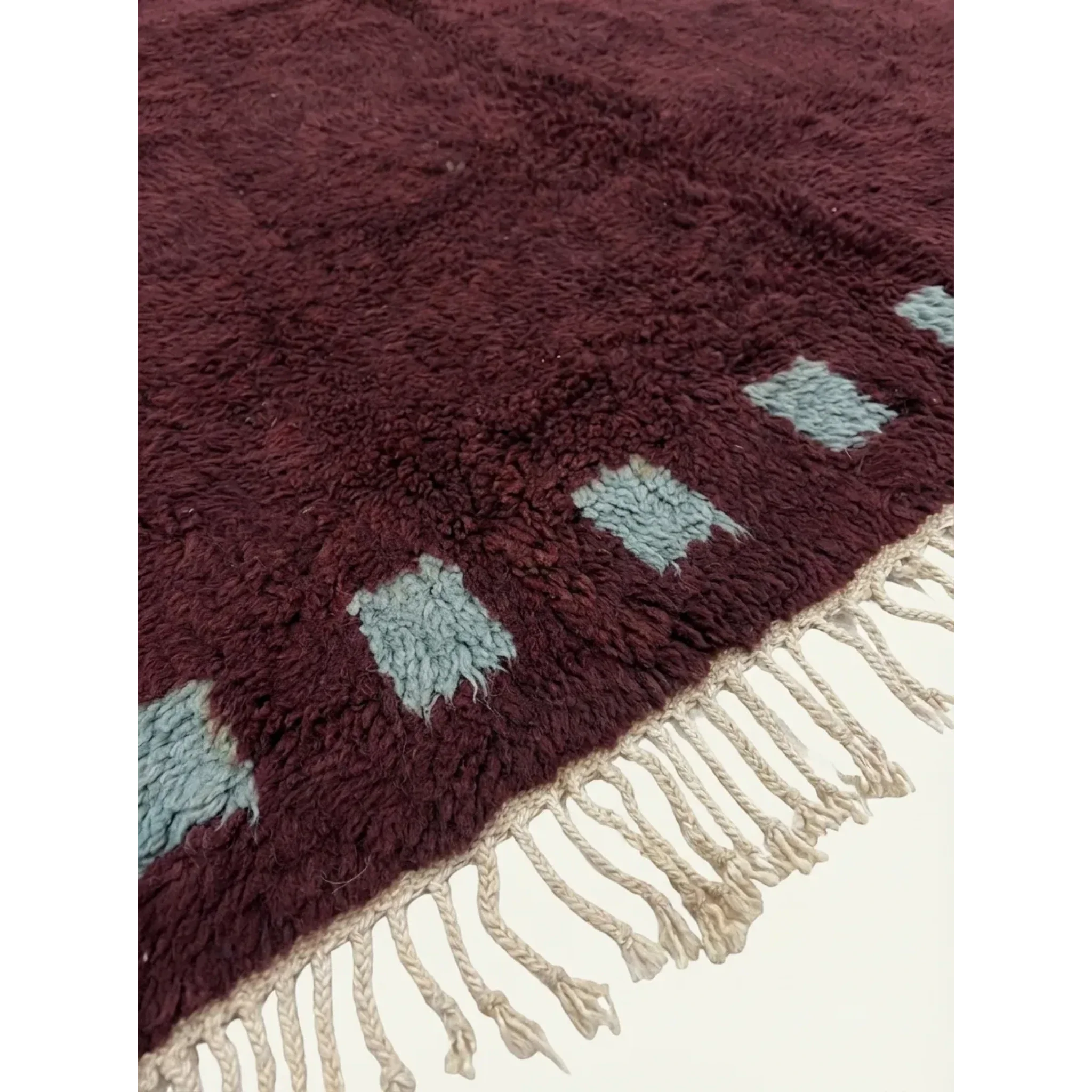 Close-up of the burgundy and ivory border block motif on the Idir rug.