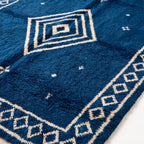 Close-up of concentric diamond motif showing pile texture and nested rectangle outlines in ivory on indigo