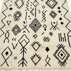 Ivory Azilal rug Afelki with black tribal pattern, wool texture detail
