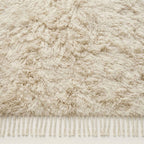 Detailed view of ivory Beni Ourain soft undyed wool pile and tassel fringe