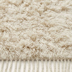 Close-up of ivory Beni Ourain pile texture showing knotted wool and fringe
