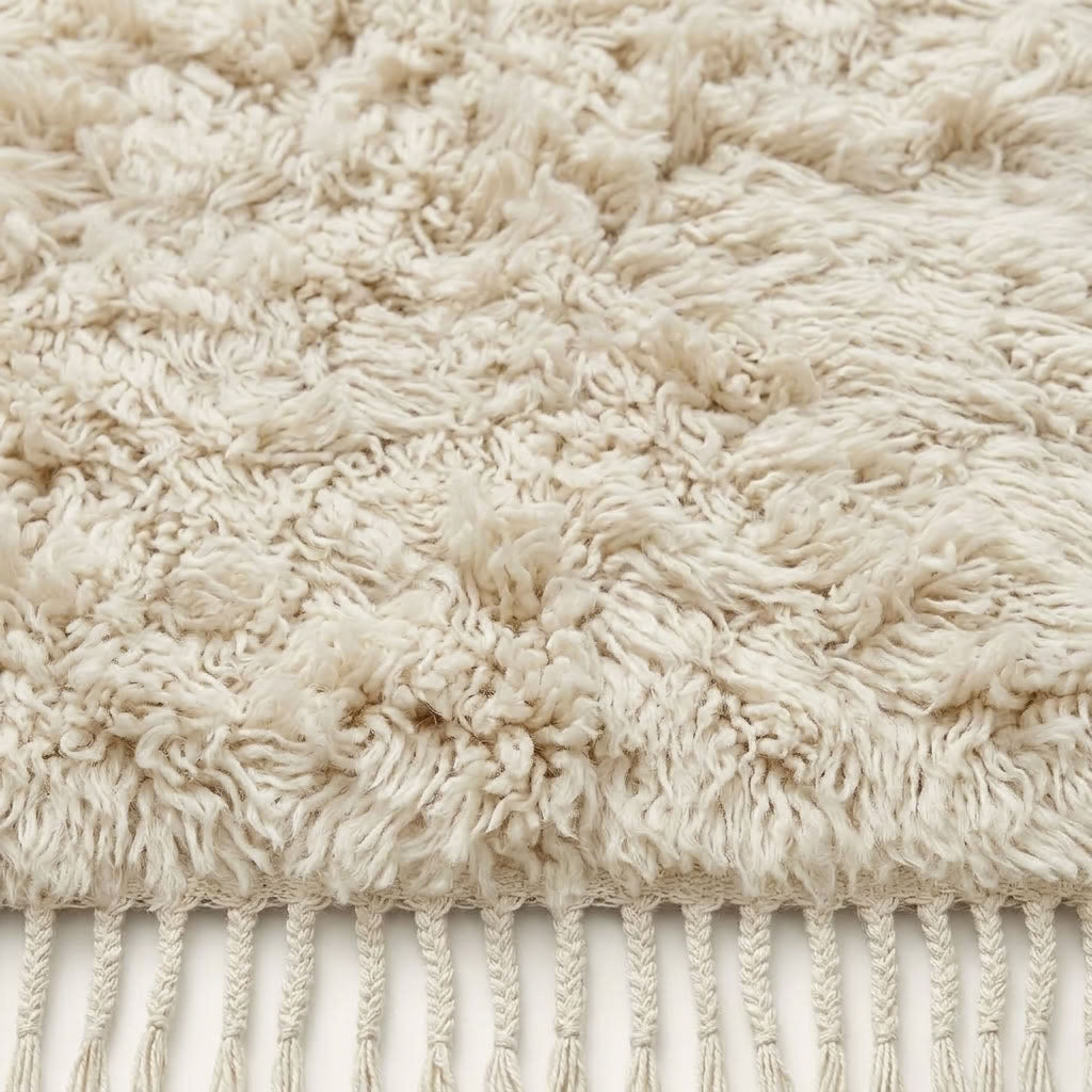Close-up of ivory Beni Ourain pile texture showing knotted wool and fringe