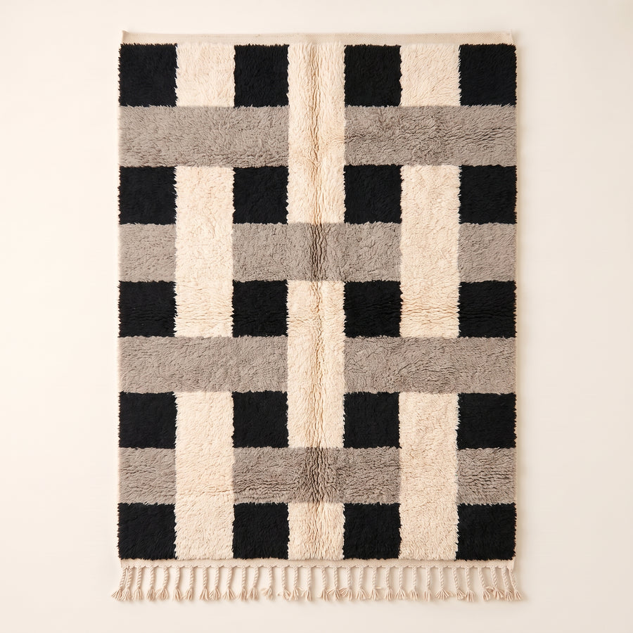 Ivory, black and grey Beni Ourain rug with checkerboard blocks pattern, flat lay on plain background