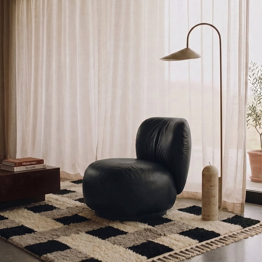 Tinhinan checkerboard rug in room setting with black leather chair and arc lamp