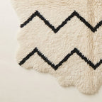 Corner view of Beni Ourain rug showing scalloped edges and hand-knotted fringe with chevron pattern