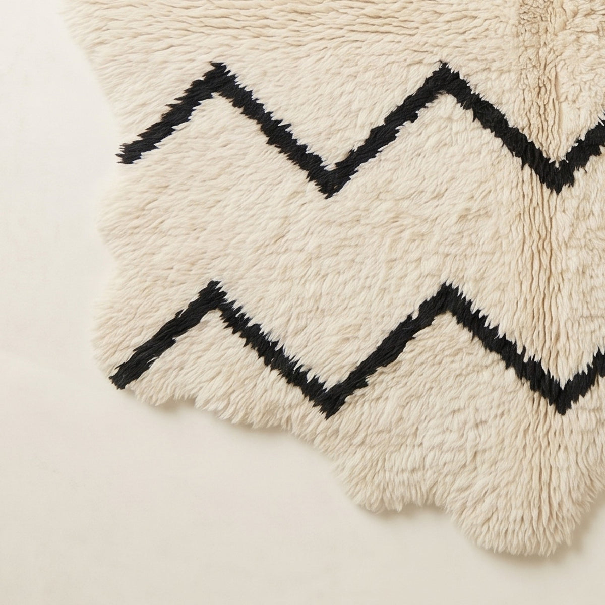 Corner view of Beni Ourain rug showing scalloped edges and hand-knotted fringe with chevron pattern