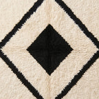 Angled texture detail of nested diamond motif showing black and ivory wool pile construction