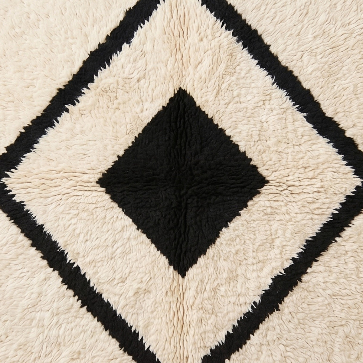 Angled texture detail of nested diamond motif showing black and ivory wool pile construction