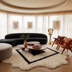 Ivory and black diamond Beni Ourain rug in modern living room with black curved sofa and wood furniture