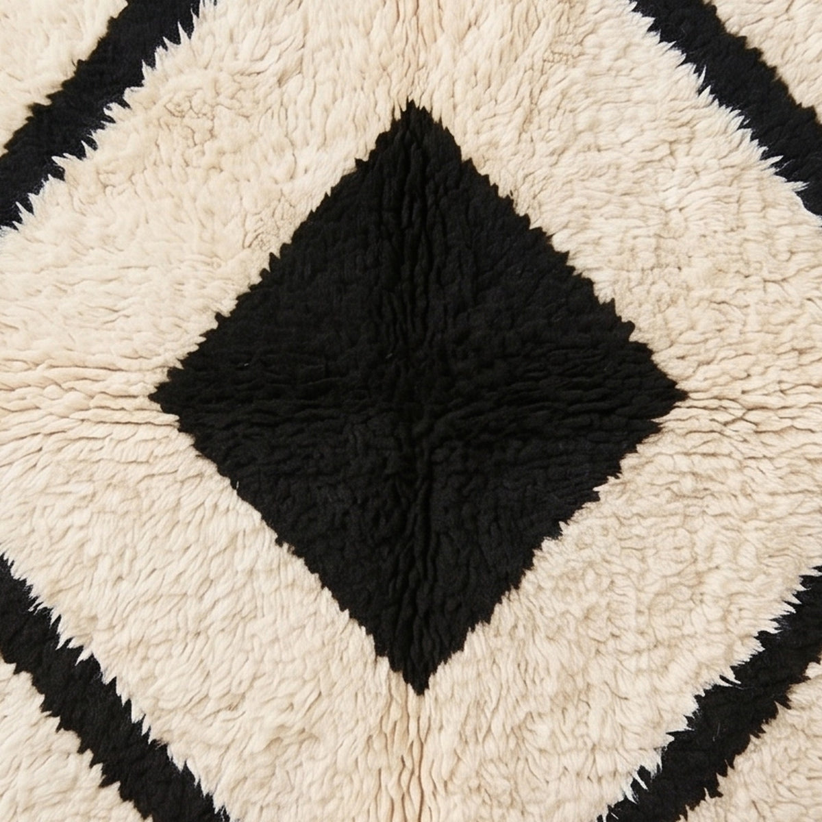 Close-up detail of inner black diamond and surrounding cream bands with hand-knotted wool pile