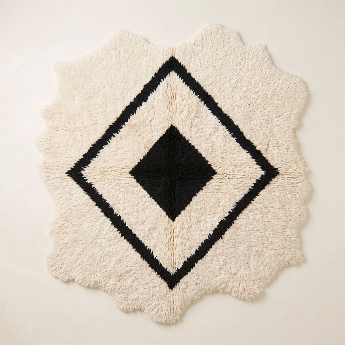 Ivory and black Beni Ourain rug with nested diamond lattice design and irregular scalloped edges, full flat view