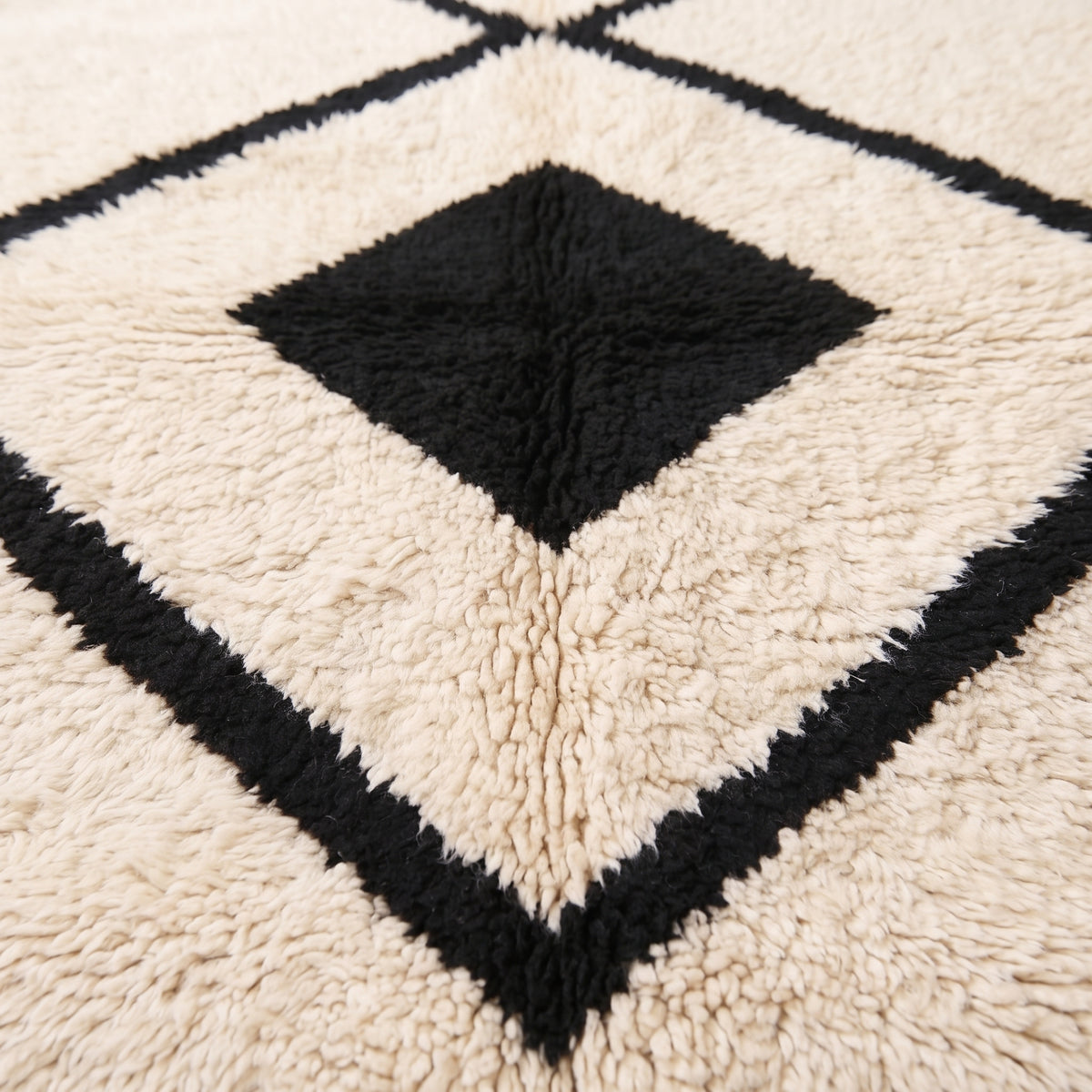 Close-up texture detail of black and ivory wool pile showing hand-knotted construction and depth