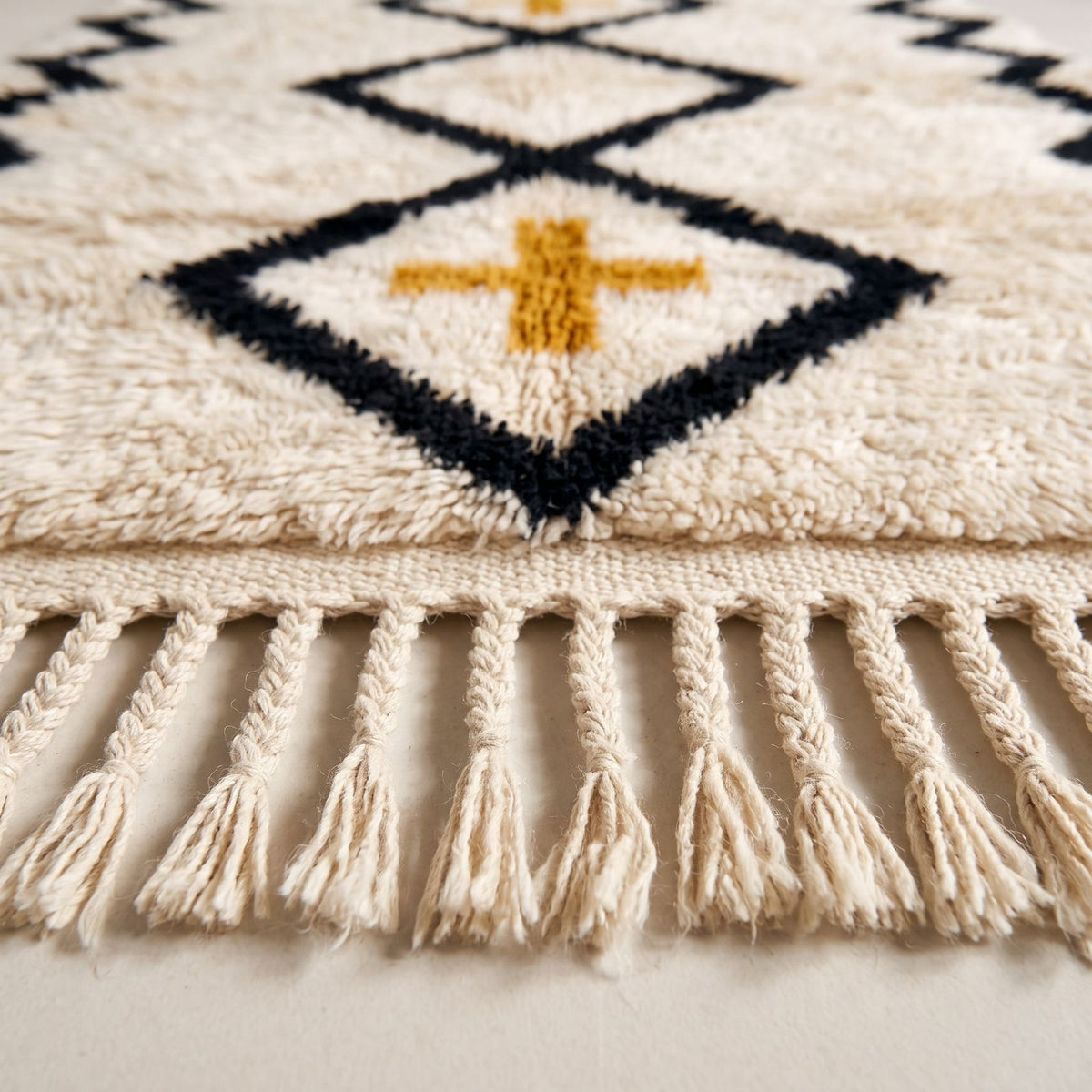 Close-up of diamond lattice and gold cross with cream fringe detail on Beni Ourain rug