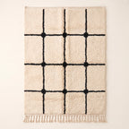 Ivory Beni Ourain rug with black grid lattice and knots, flat lay
