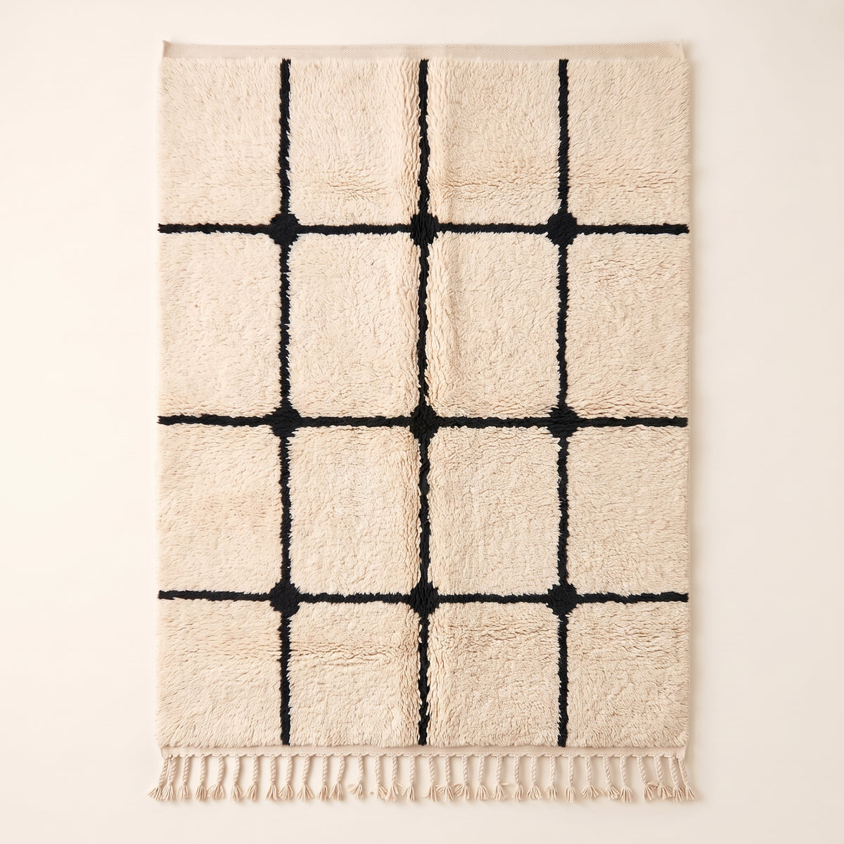 Ivory Beni Ourain rug with black grid lattice and knots, flat lay
