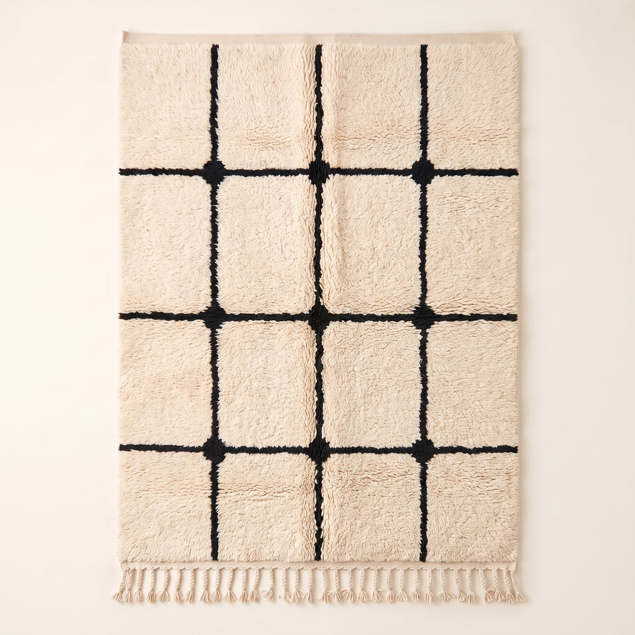 Ivory Beni Ourain rug with black grid lattice and knots, flat lay