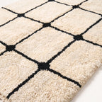 Close-up of thick wool pile and black lattice lines on ivory ground