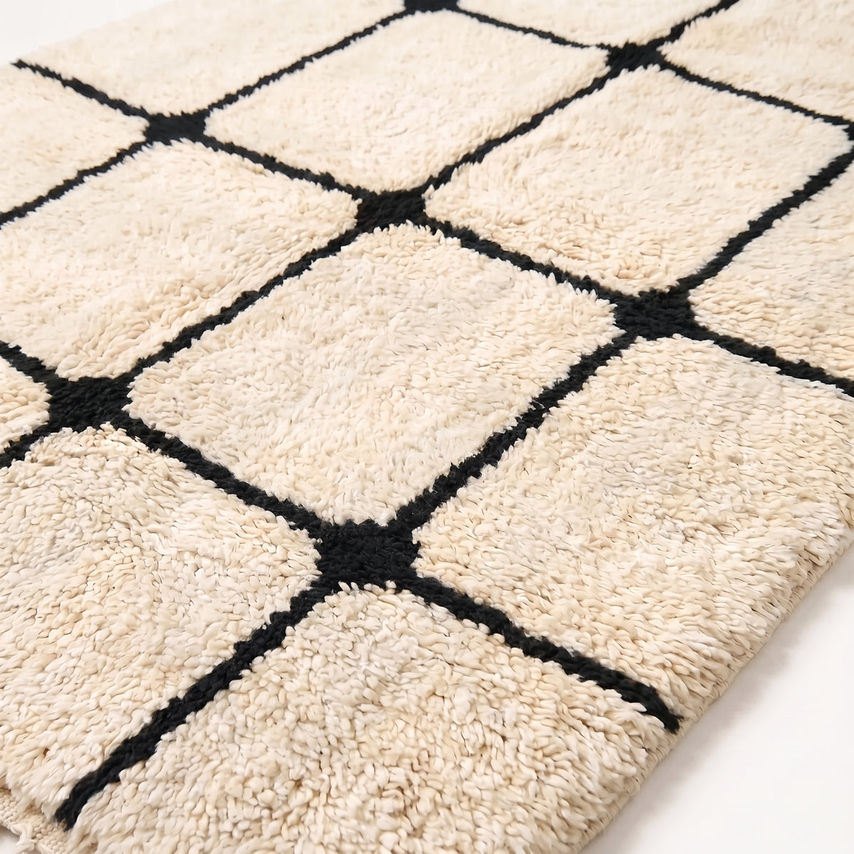 Close-up of thick wool pile and black lattice lines on ivory ground